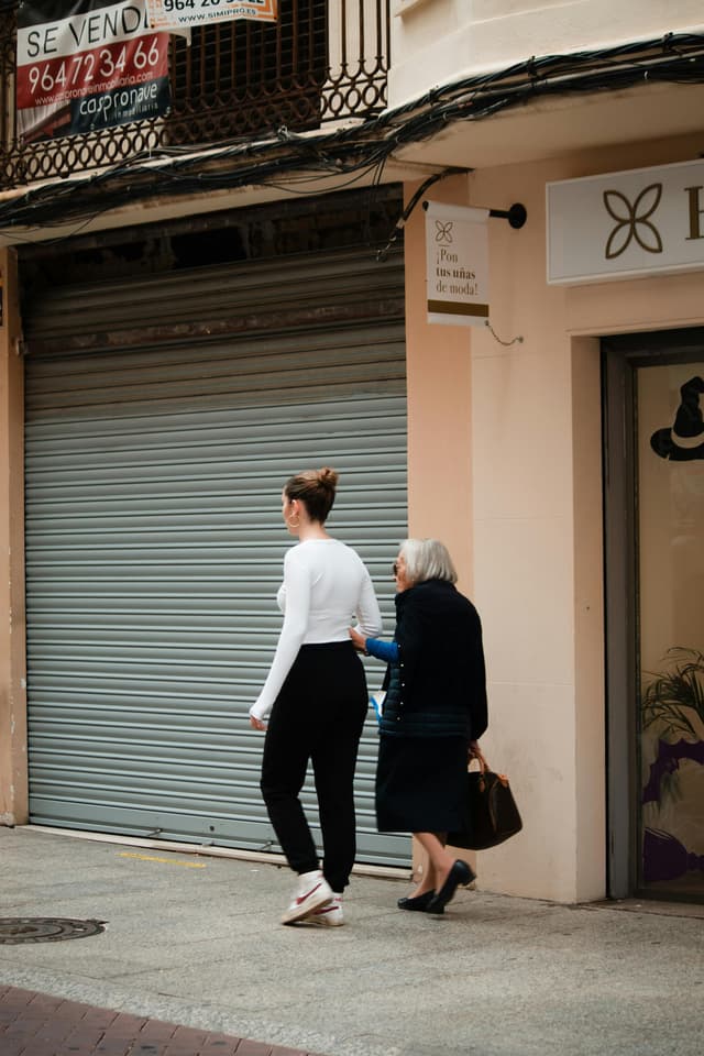 A younger woman walking beside an older woman on a city sidewalk
