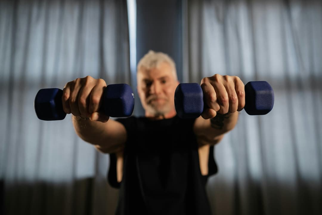 An older man lifting light dumbbells at home