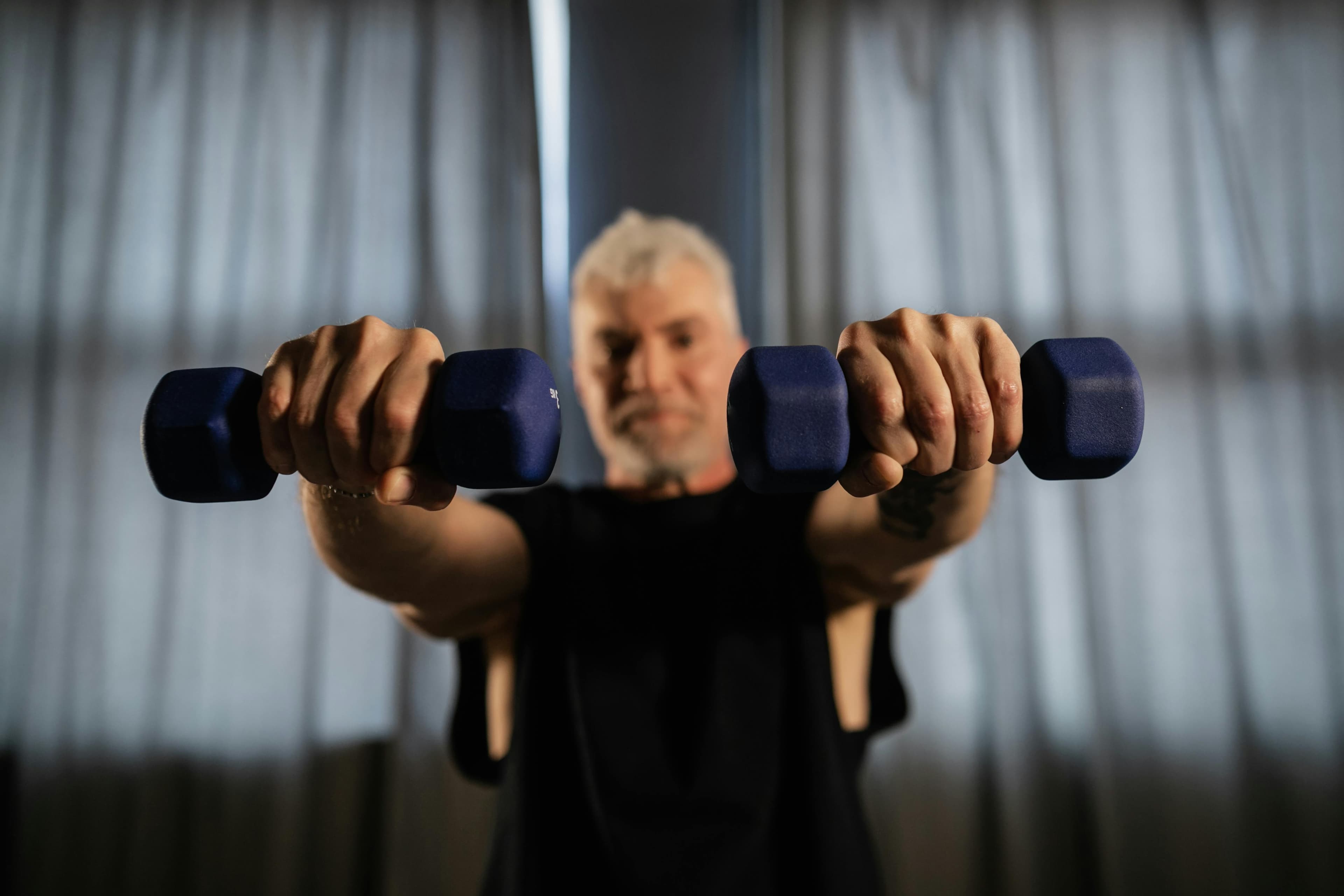 An older adult building strength with dumbbells at home